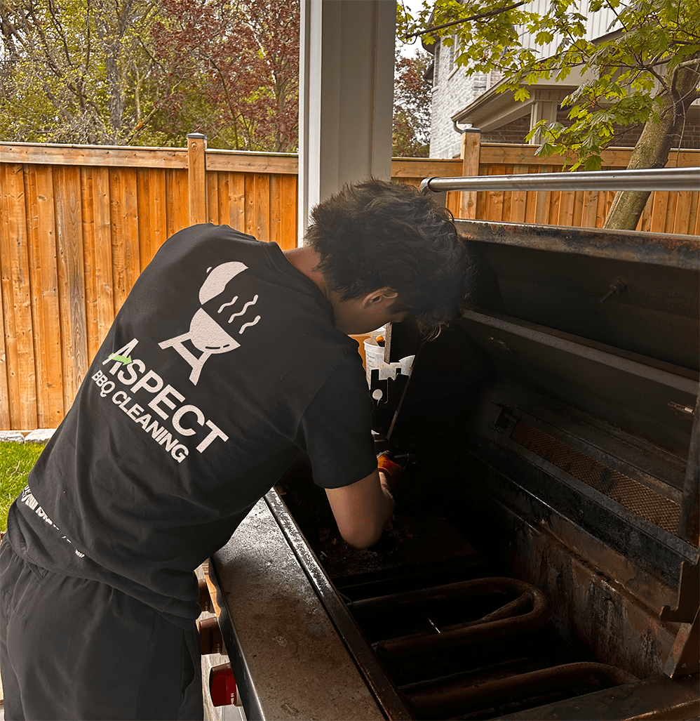 An Aspect technician cleaning inside a built-in grill